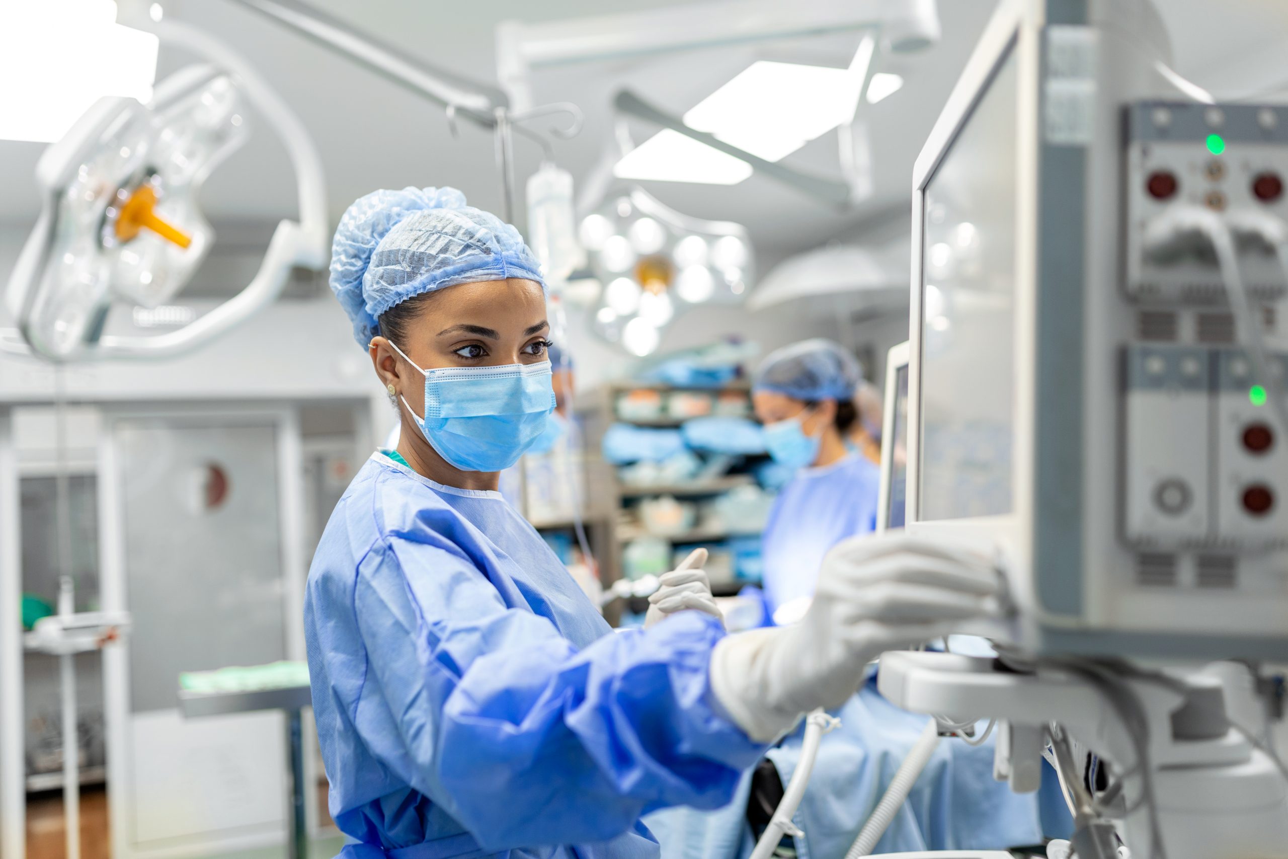 Anesthetist Working In Operating Theatre Wearing Protecive Gear checking monitors while sedating patient before surgical procedure in hospital » ProSalud.me - Pro Salud equipamiento hospitalario » ProSalud.me - Pro Salud