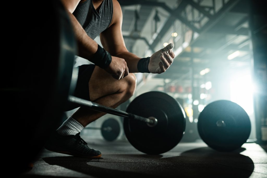 En busca del equilibrio perfecto: Cómo combinar ejercicio y suplementos para una vida saludable 2 vista angulo hombre musculoso irreconocible preparandose levantar barra club salud
